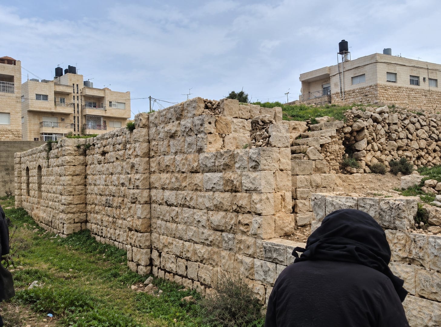 Ruined stone walls with surrounding buildings beyond