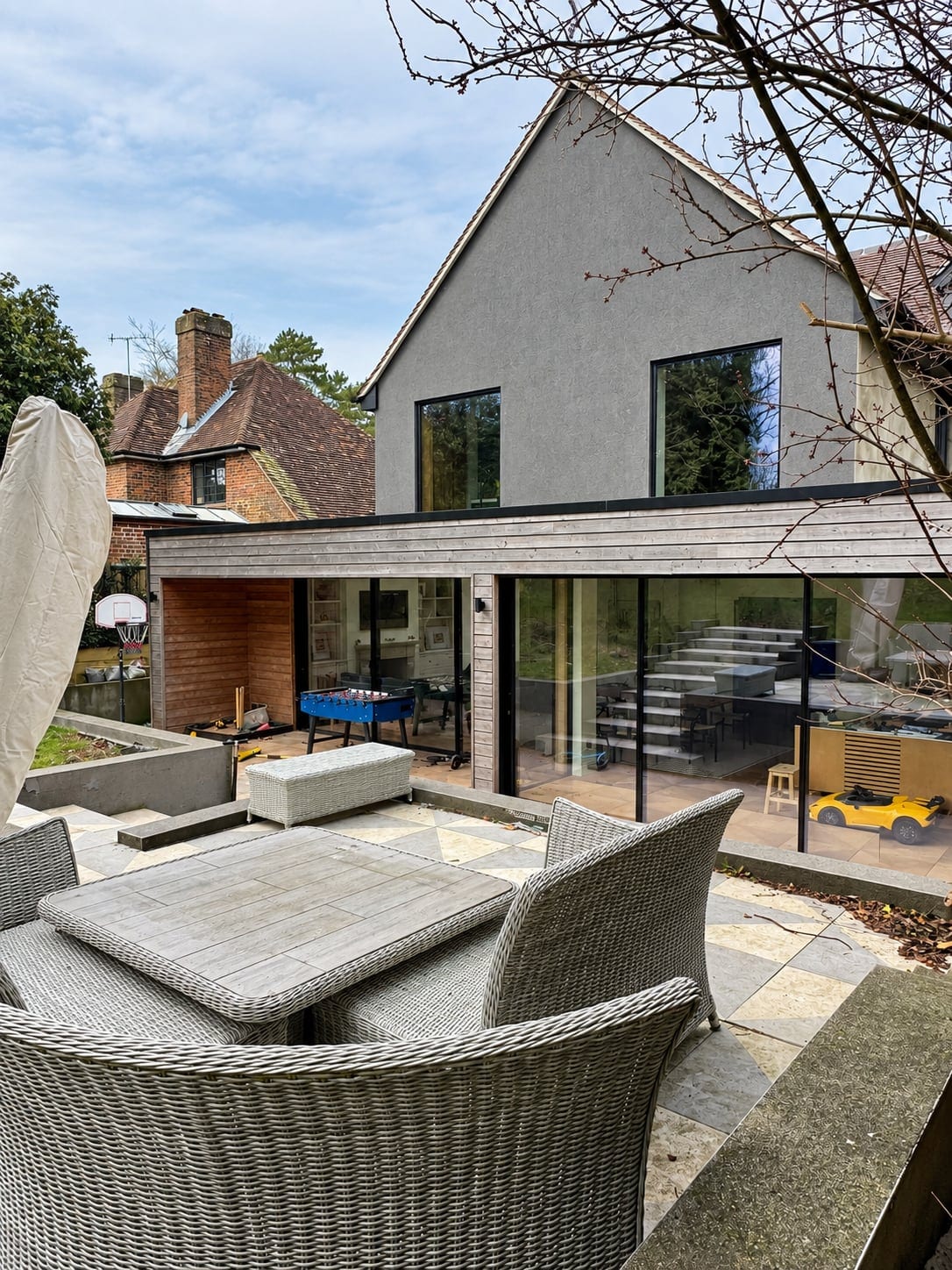 View across the terrace to the extension and the rendered gable, with outdoor seating in the foreground