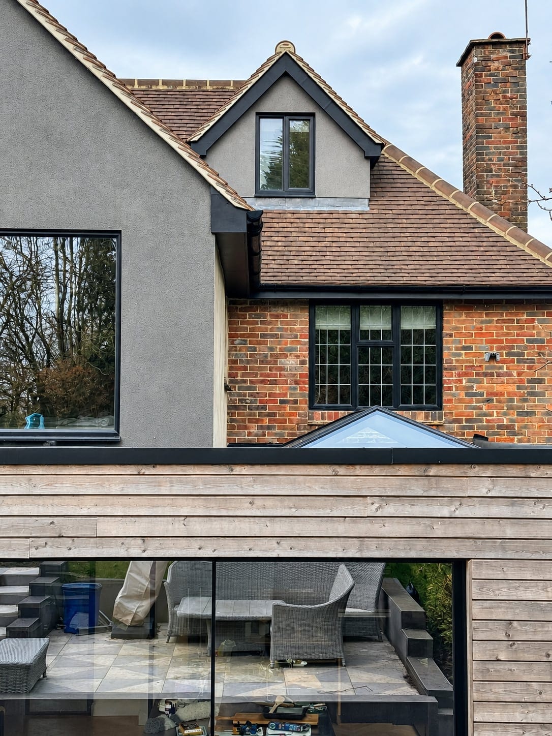 Closer view of the rear: tall glazing in the rendered gable above the timber-clad extension