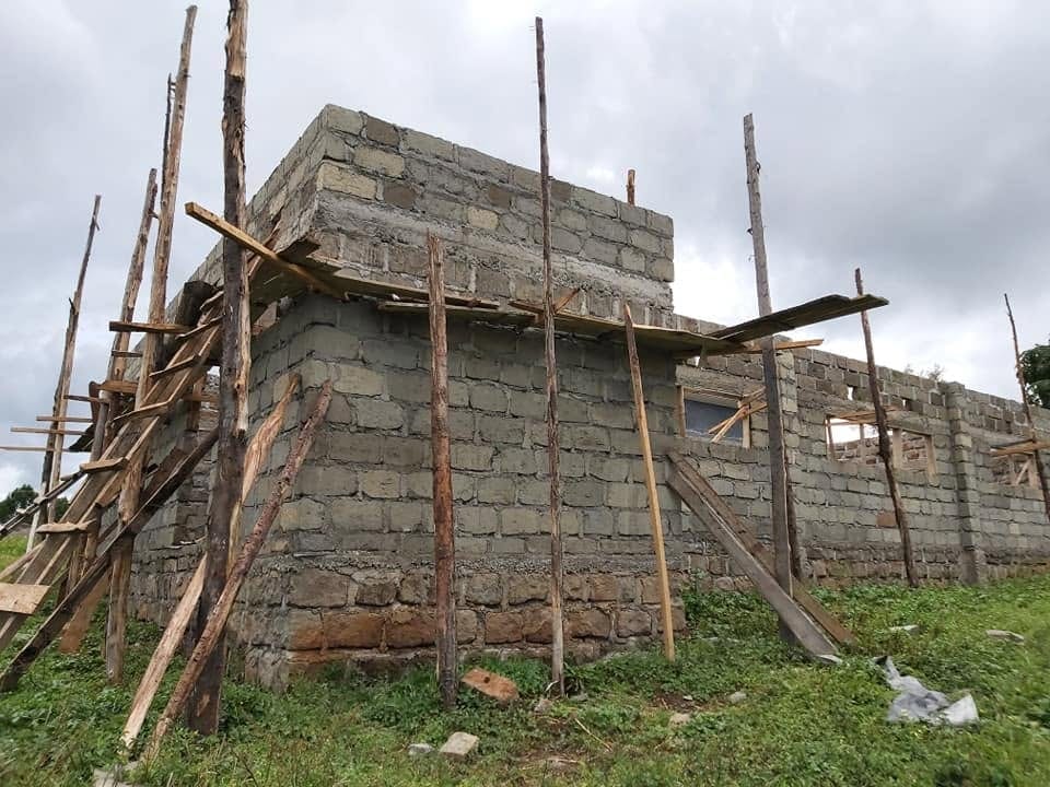 Construction: masonry walls rising behind timber-pole scaffolding