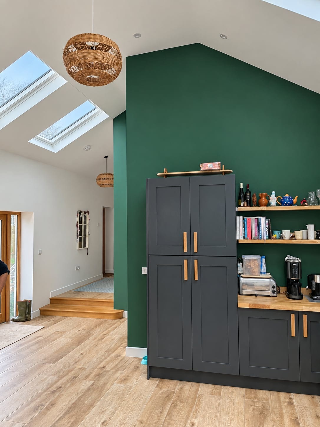 Dark kitchen cabinets and open shelving against a deep green wall