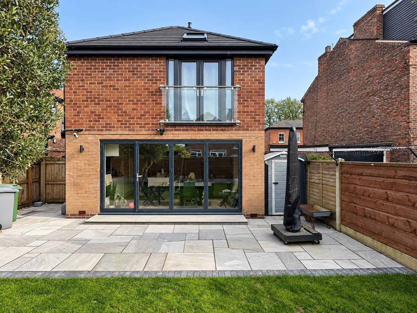 Rear of the brick house: first-floor extension with a glazed Juliet balcony above wide sliding doors