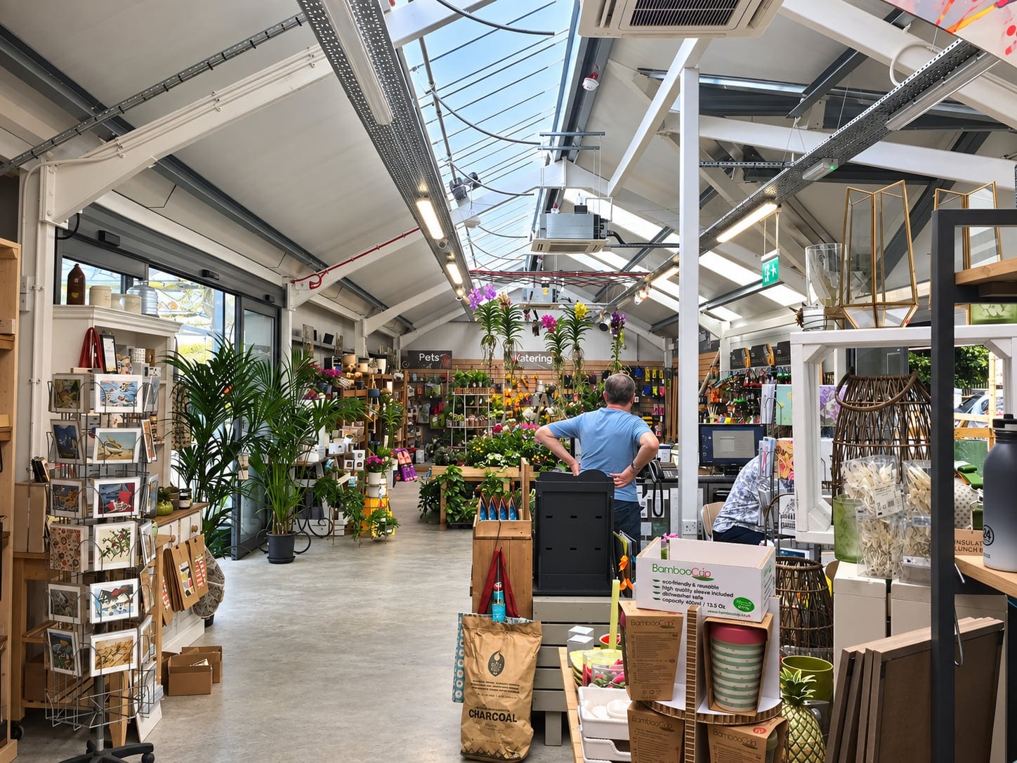 Inside the garden centre shop, with plants, cards and a glazed roof