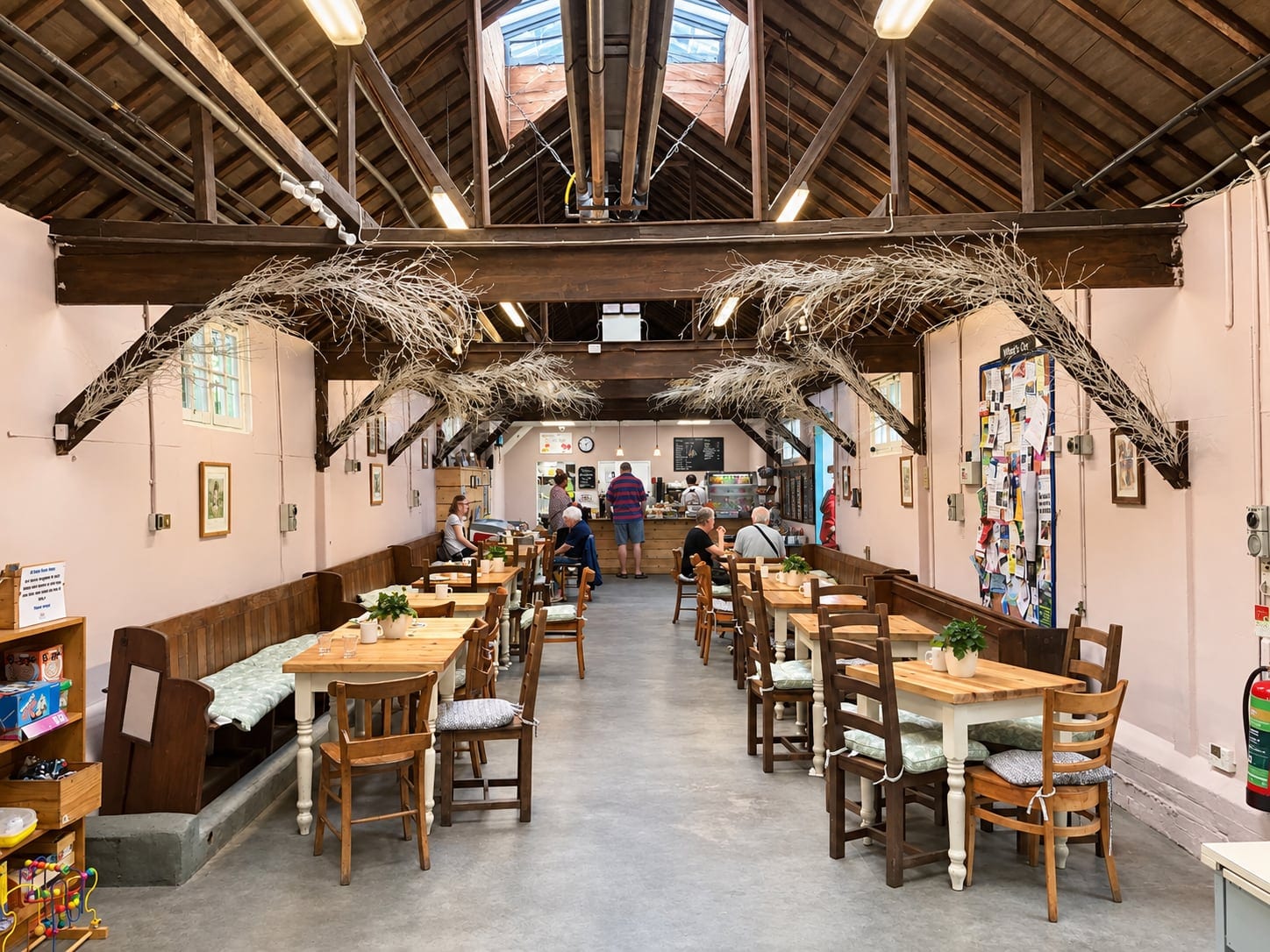 The café: timber tables under exposed roof trusses decorated with branches