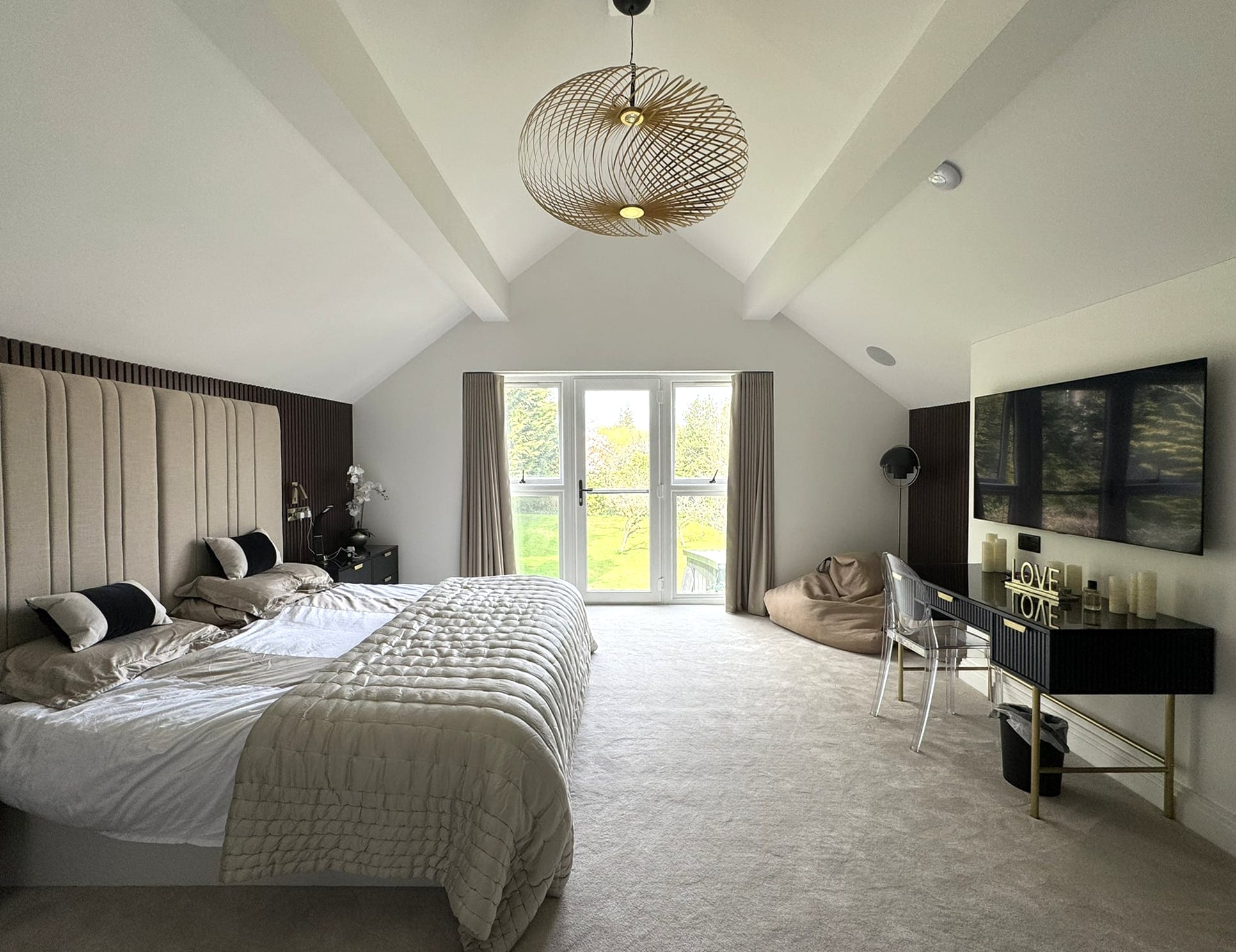 Main bedroom under a vaulted ceiling with French doors
