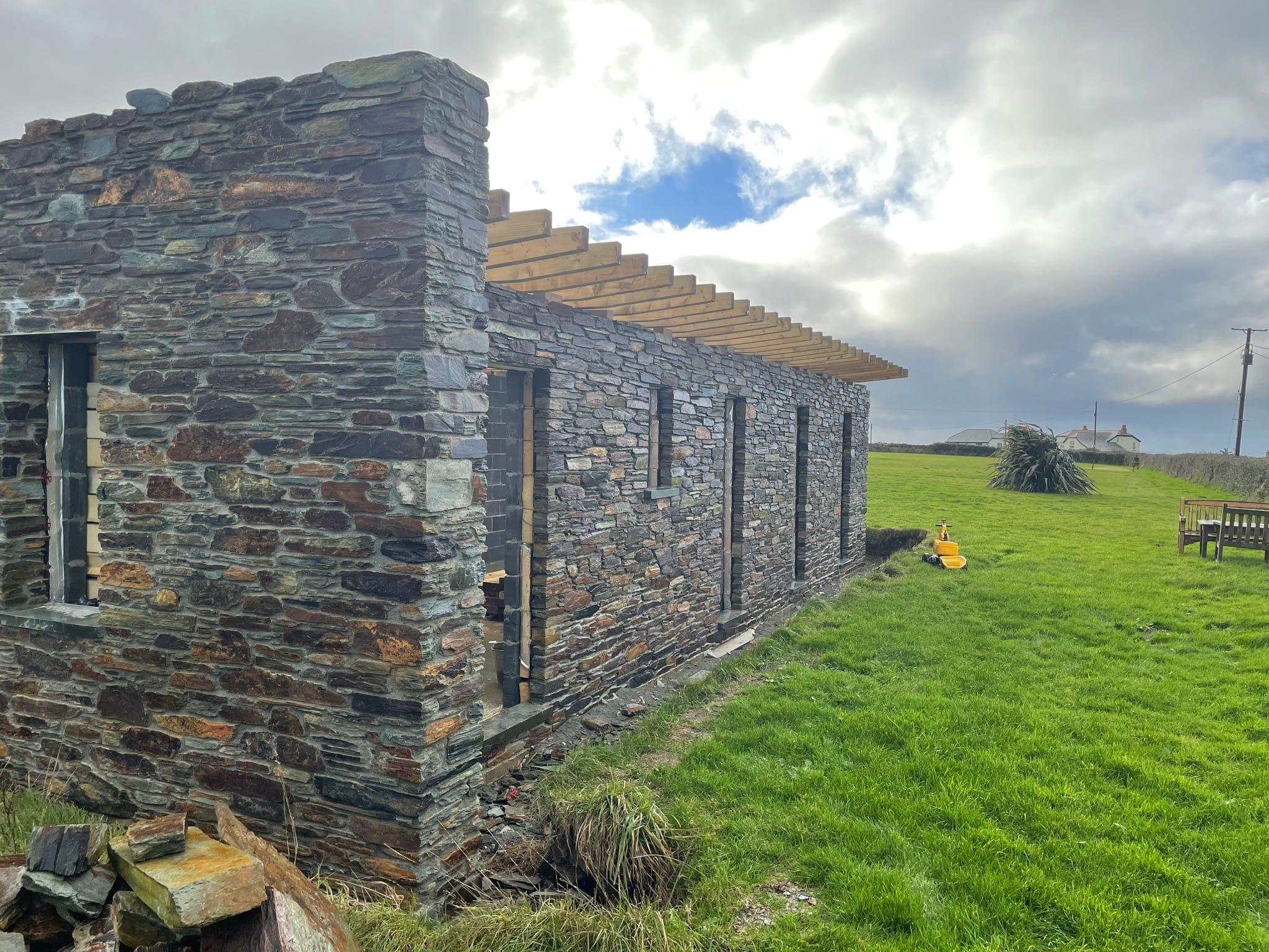 Construction: local slate-stone walling at a corner, with roof joists above