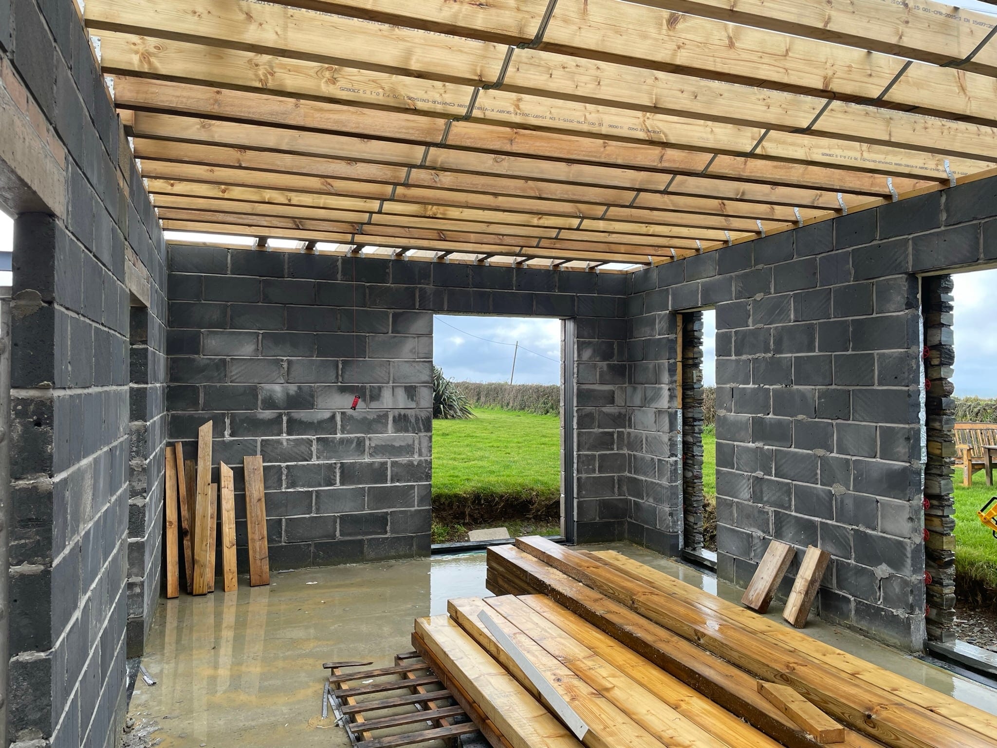 Construction: interior with roof joists and openings framing the field beyond