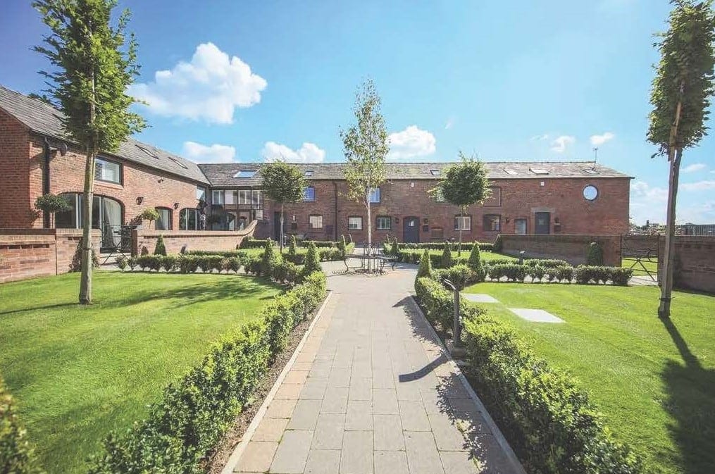 Converted brick farm buildings around a landscaped courtyard