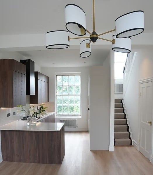 Kitchen and stair inside a listed building, beneath a modern chandelier