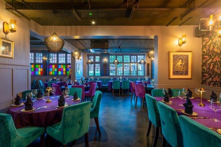 Restaurant dining room with teal velvet chairs and stained-glass screens