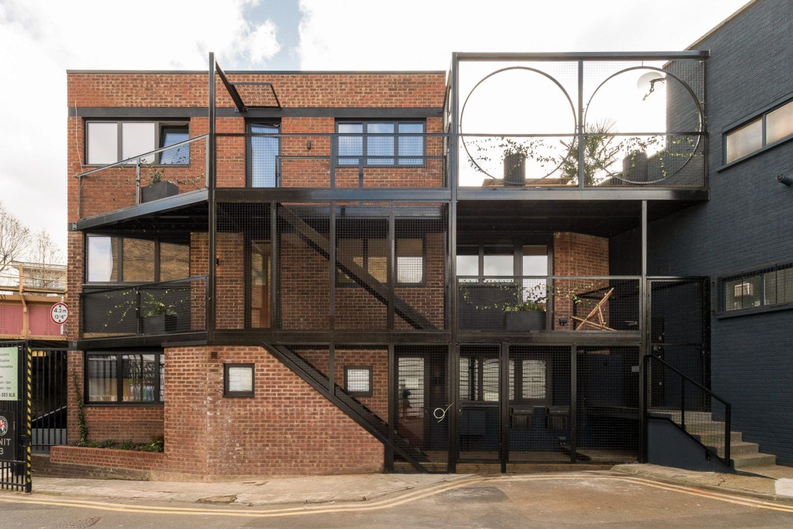 Brick house with black steel balconies and circular openings