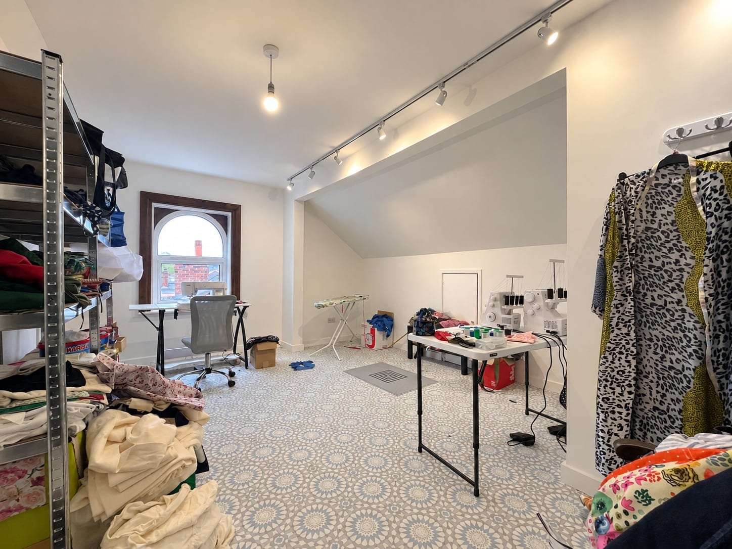 Wide view of the loft studio with cutting table, track lighting and fabric storage