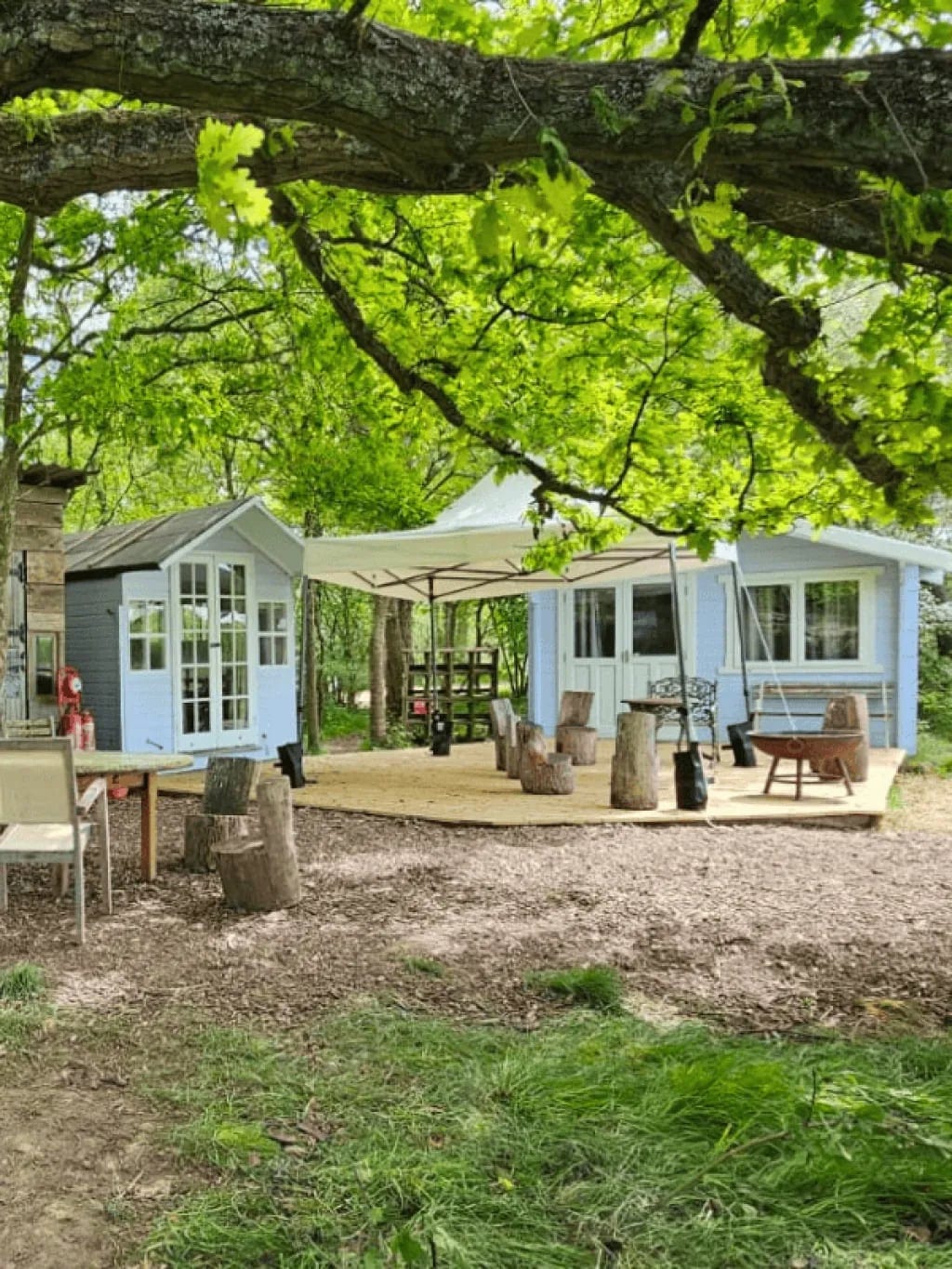 Pale blue timber cabins with a shared deck and outdoor seating