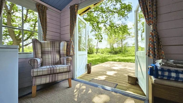 Inside a cabin, looking out through open doors to the deck and trees