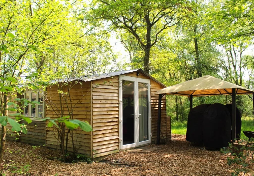 Timber-clad cabin with glazed doors beside a covered seating area
