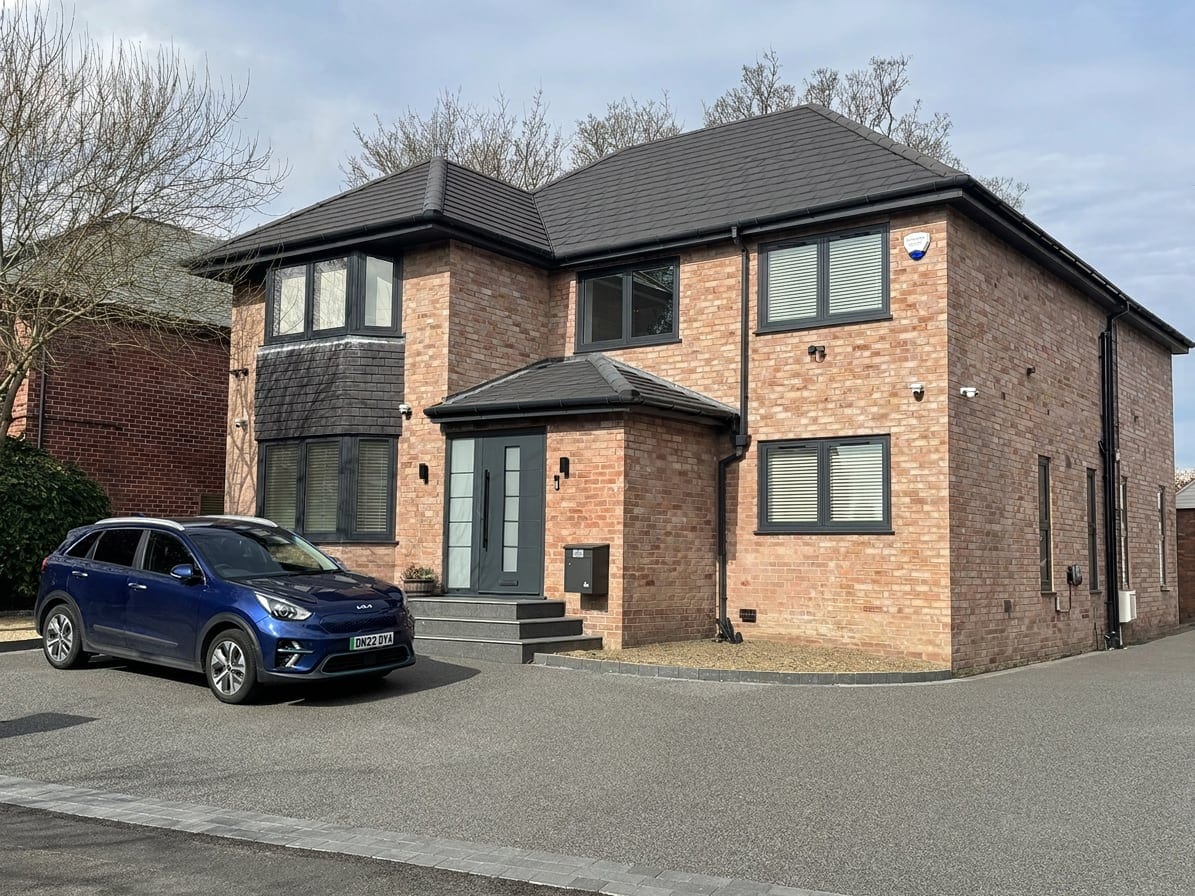 Front of the extended brick house with anthracite windows and a new entrance porch
